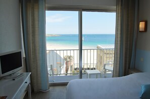 Quarto de hotel com varanda, cama, televisão e escrivaninha.