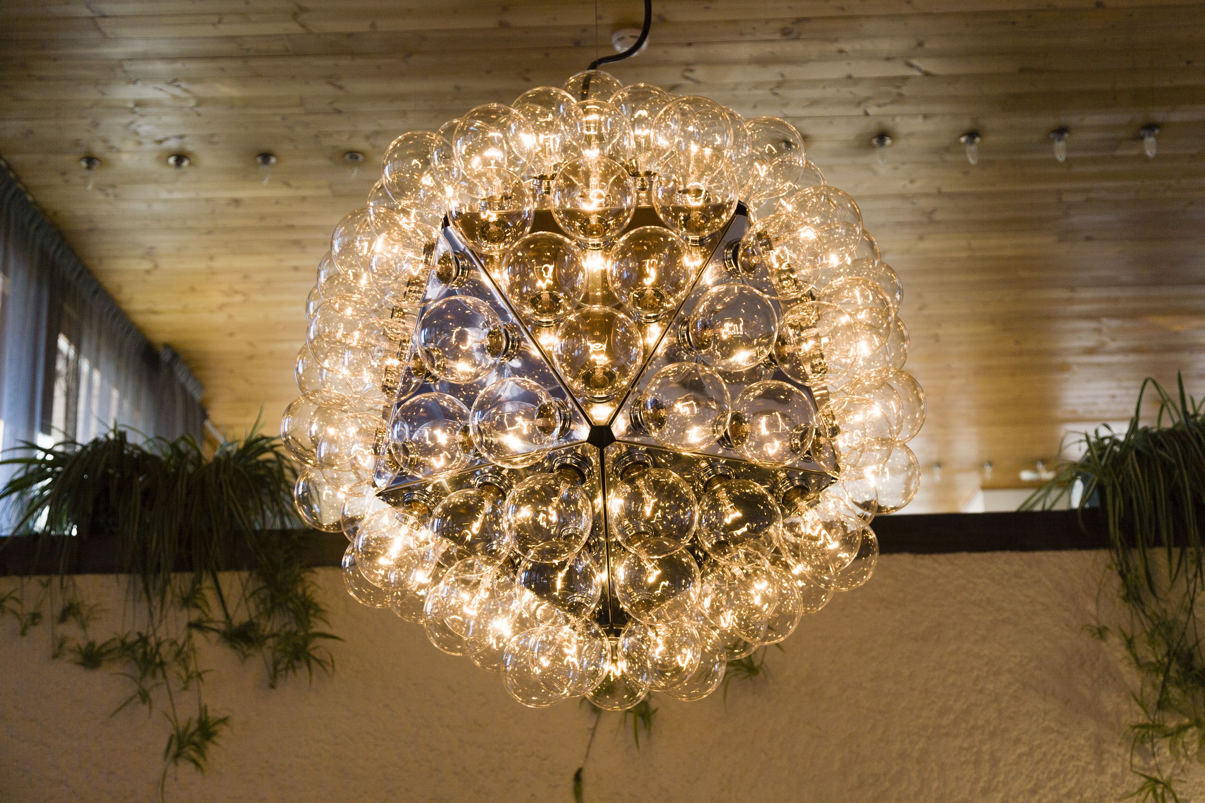 En kristallkrona med flera sfäriska glödlampor som hänger från ett trätak.