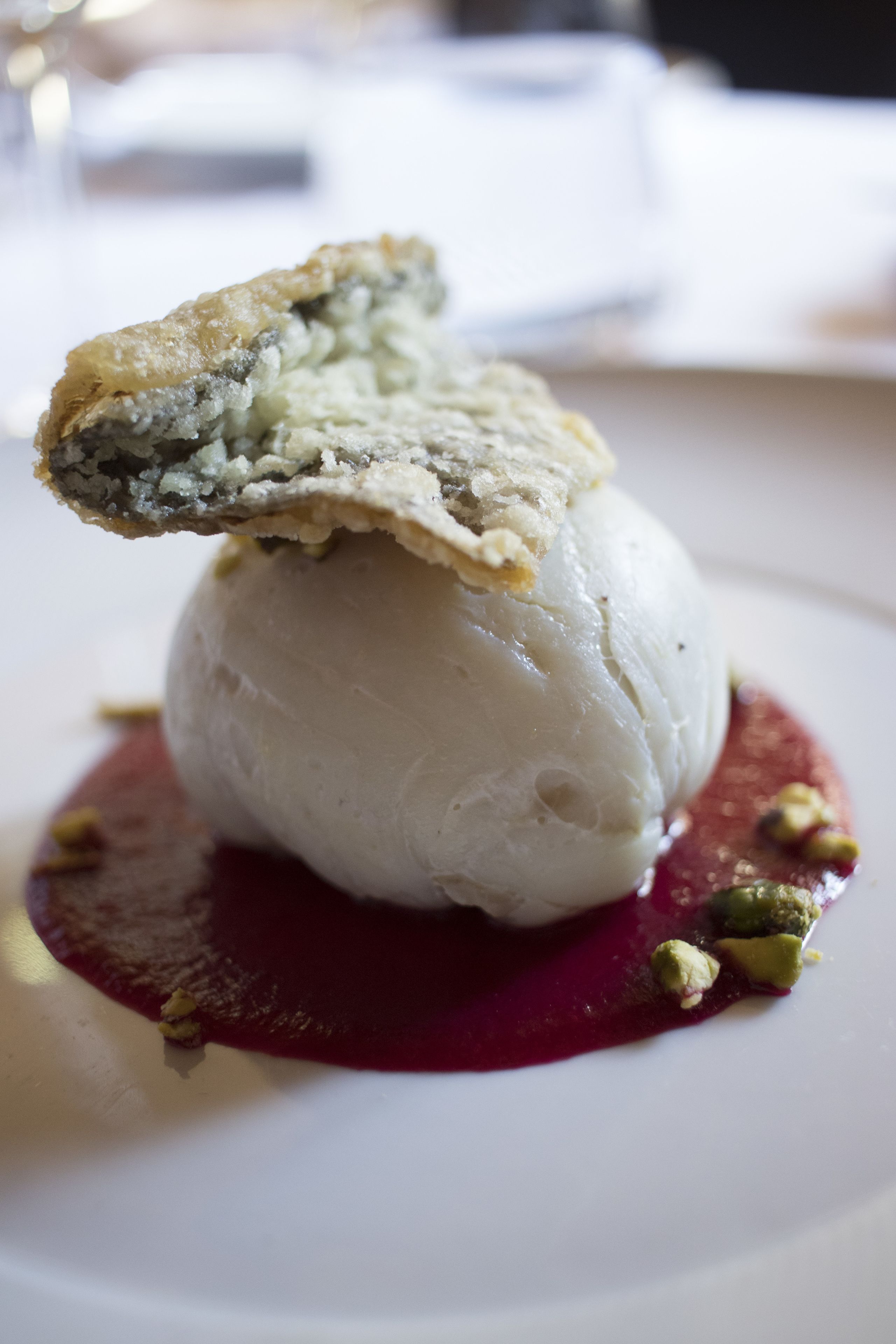 A dessert with a scoop of ice cream on a plate with a red sauce and a piece of cake on top.