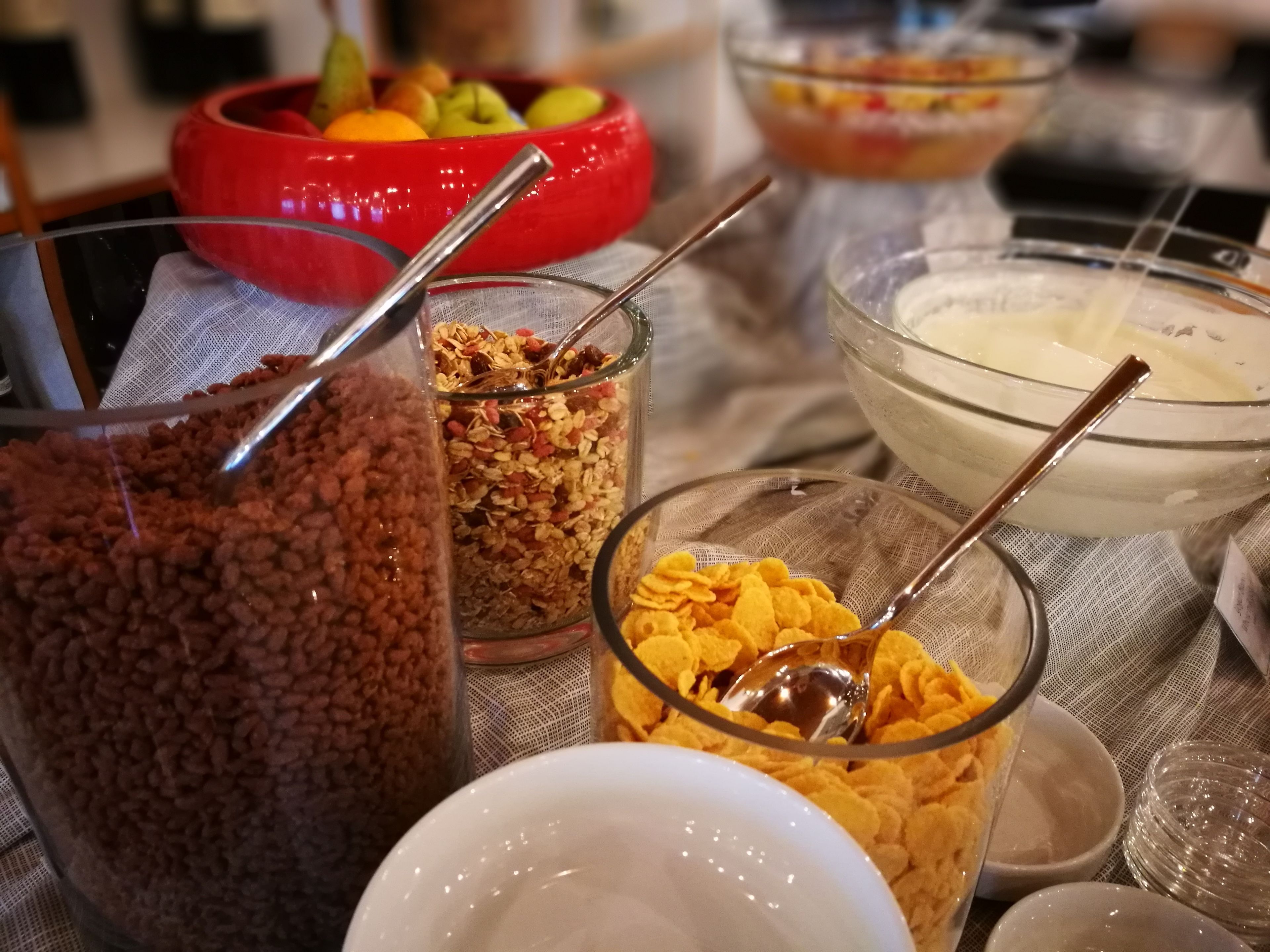 A table with various food items including cereal, granola, and a bowl of fruit.