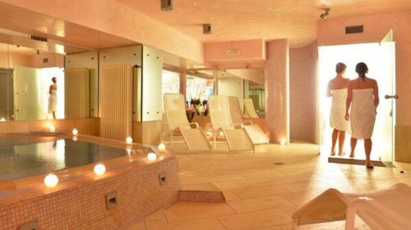 A spa area with a hot tub, lounge chairs, and a mirror reflecting the room.