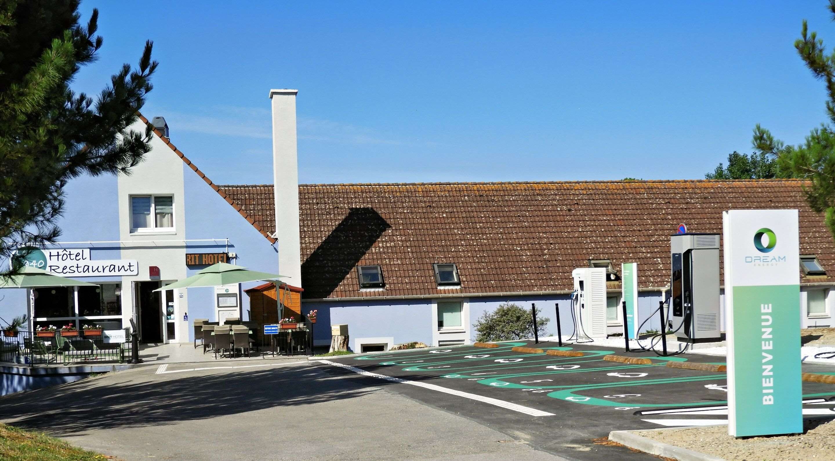 A hotel with a restaurant, a gas station, and a sign for 'BIENVENUE'.