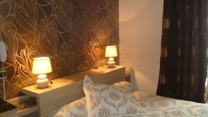 A hotel room with a bed, two bedside tables with lamps, a telephone, and a patterned wall. - Hôtel Media (Paris)