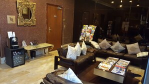 A hotel lobby with a seating area, a coffee machine, and a magazine rack. - Hôtel Media (Paris)