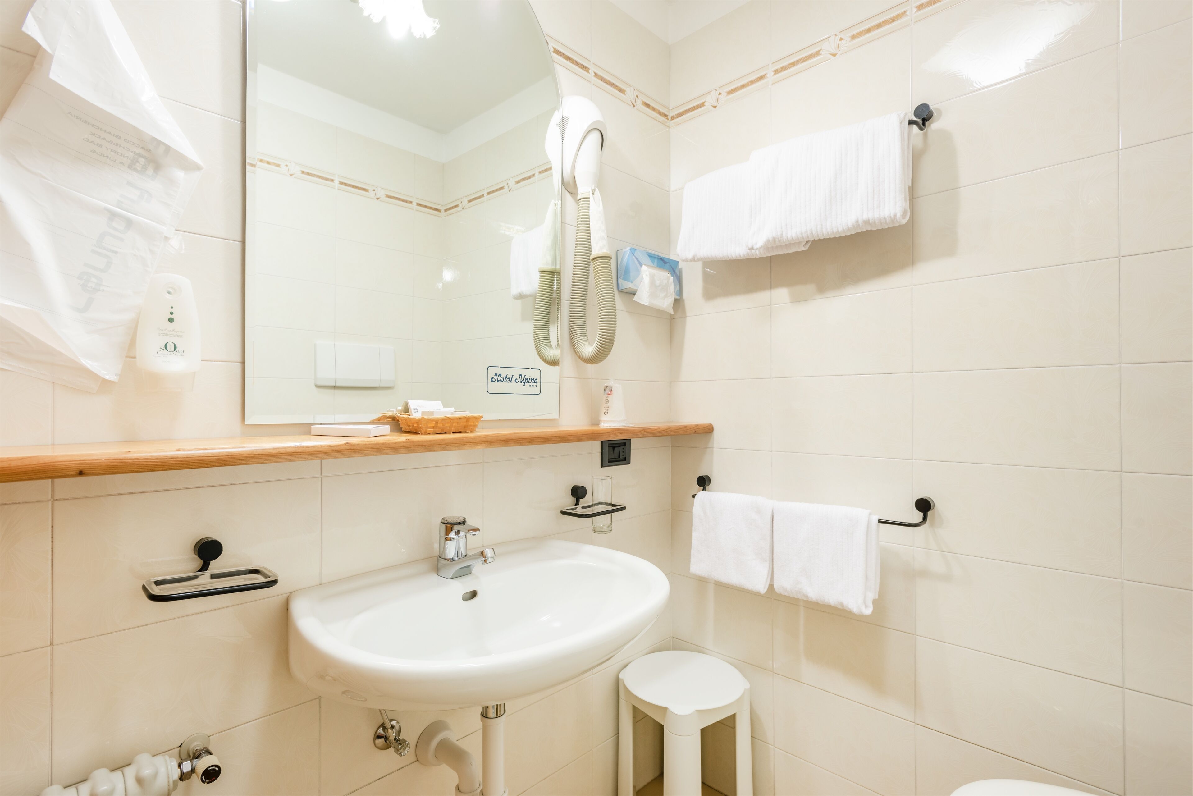 A bathroom with a sink, mirror, towel rack, and a hairdryer.