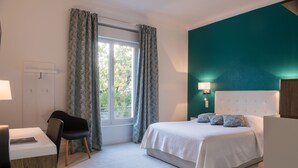 A modern hotel room with a large bed, a desk, and a chair.