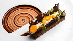 A dessert on a white plate with a chocolate swirl design.