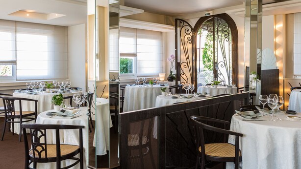 A restaurant with multiple tables set for dining, each with wine glasses and cutlery.