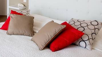 Un lit bien fait, agrémenté de plusieurs oreillers, dans une chambre d’hôtel.
