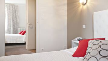 Quarto de hotel com cama, mesa de cabeceira e luminária fixada na parede.