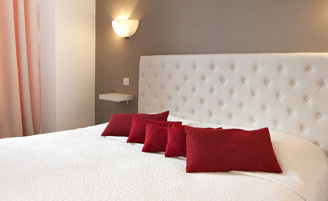 Ein Hotelzimmer mit einem großen Bett, einem weißen Kopfteil und roten Kissen.