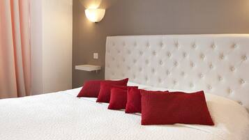 Ein Hotelzimmer mit einem großen Bett, einem weißen Kopfteil und roten Kissen.
