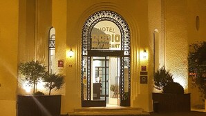 A hotel entrance with a large arched doorway, a sign reading "HOTEL RESTAURANT," and two illuminated signs on either side.