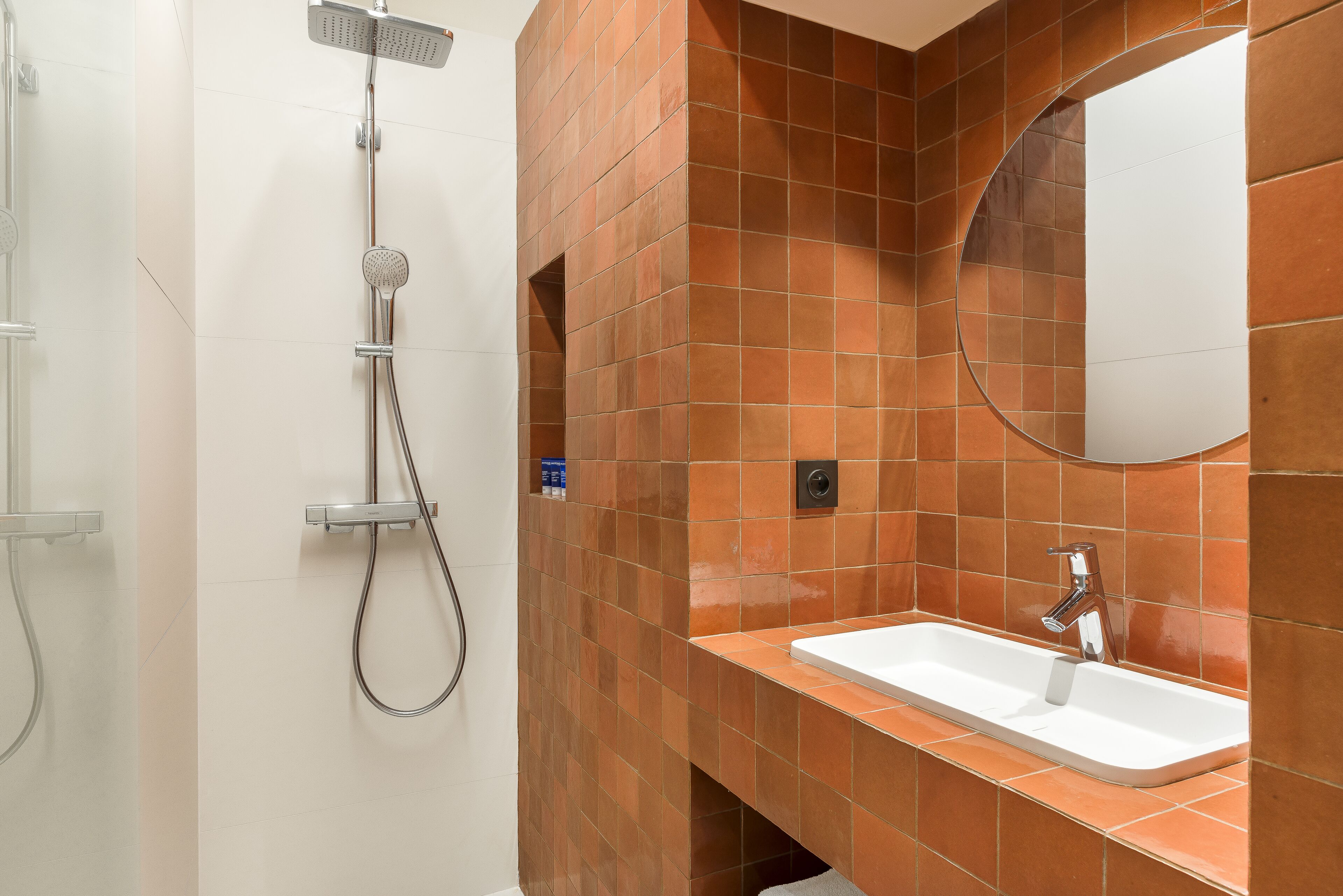 Un baño con ducha, lavamanos y espejo.