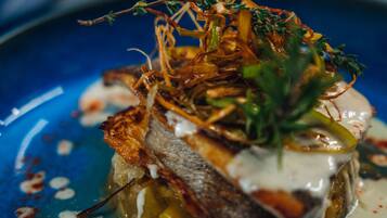 A blue plate with a fish dish, garnished with herbs and sauce.