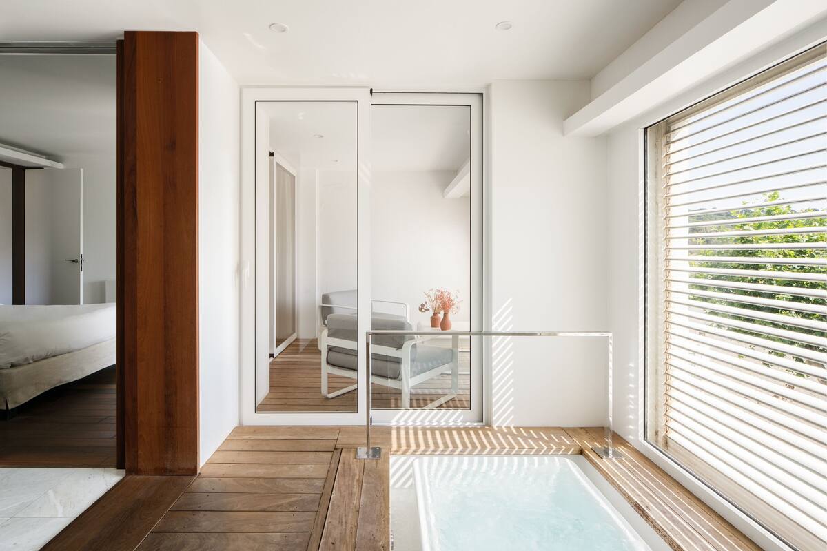 A modern bathroom with a wooden floor, a bathtub, and a glass shower enclosure.