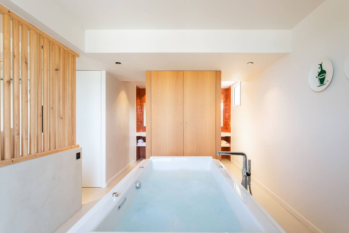 A modern bathroom with a large bathtub, wooden paneling, and a towel rack.