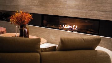 A modern living room with a fireplace, a round wooden table, and a sofa.