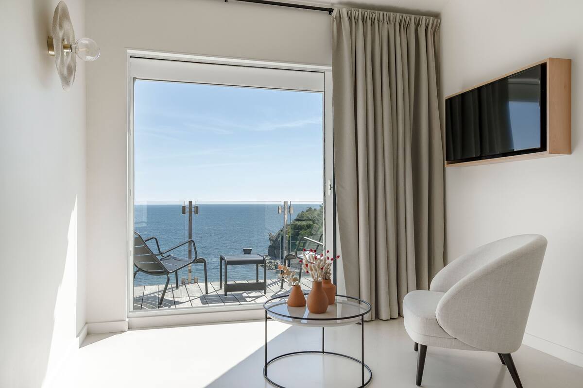 A modern room with a balcony, a TV mounted on the wall, and a chair.