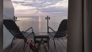 Un balcón con dos sillas mirando una puesta de sol sobre el mar.
