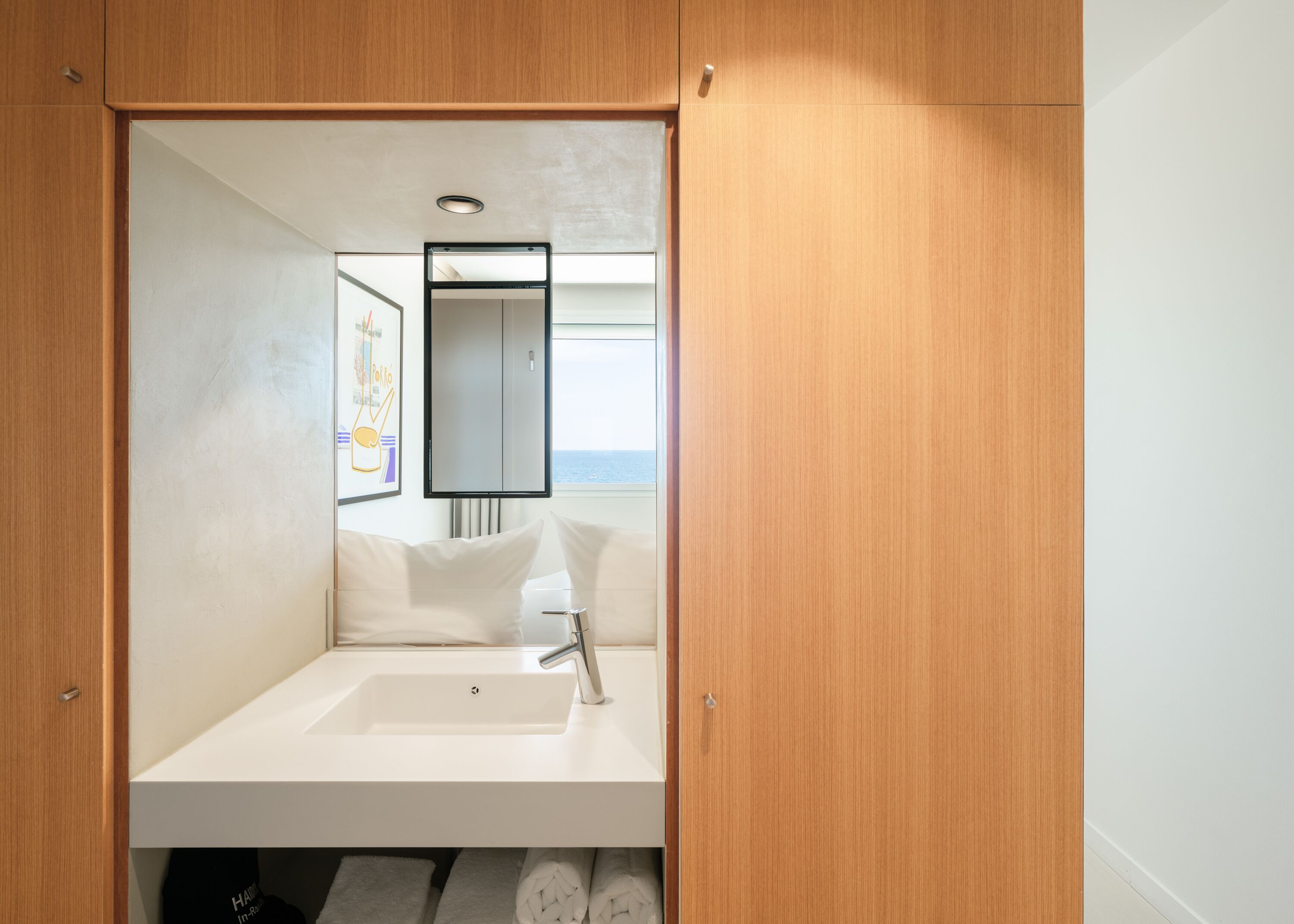 A compact bathroom with a white sink, a mirror, and a towel rack.