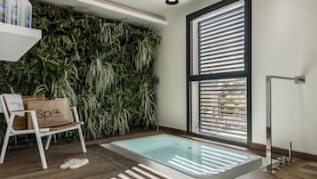 Bathroom features a large bathtub, a bench, and lush greenery.