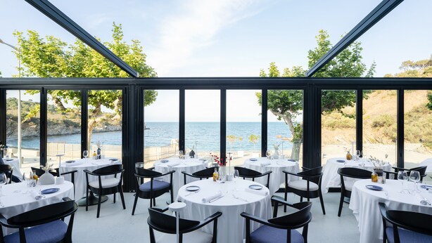 Un restaurante con mesas y sillas redondas, con vistas al mar.
