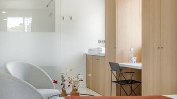 Una habitación de hotel moderna con una cama, un escritorio, una silla y un armario.