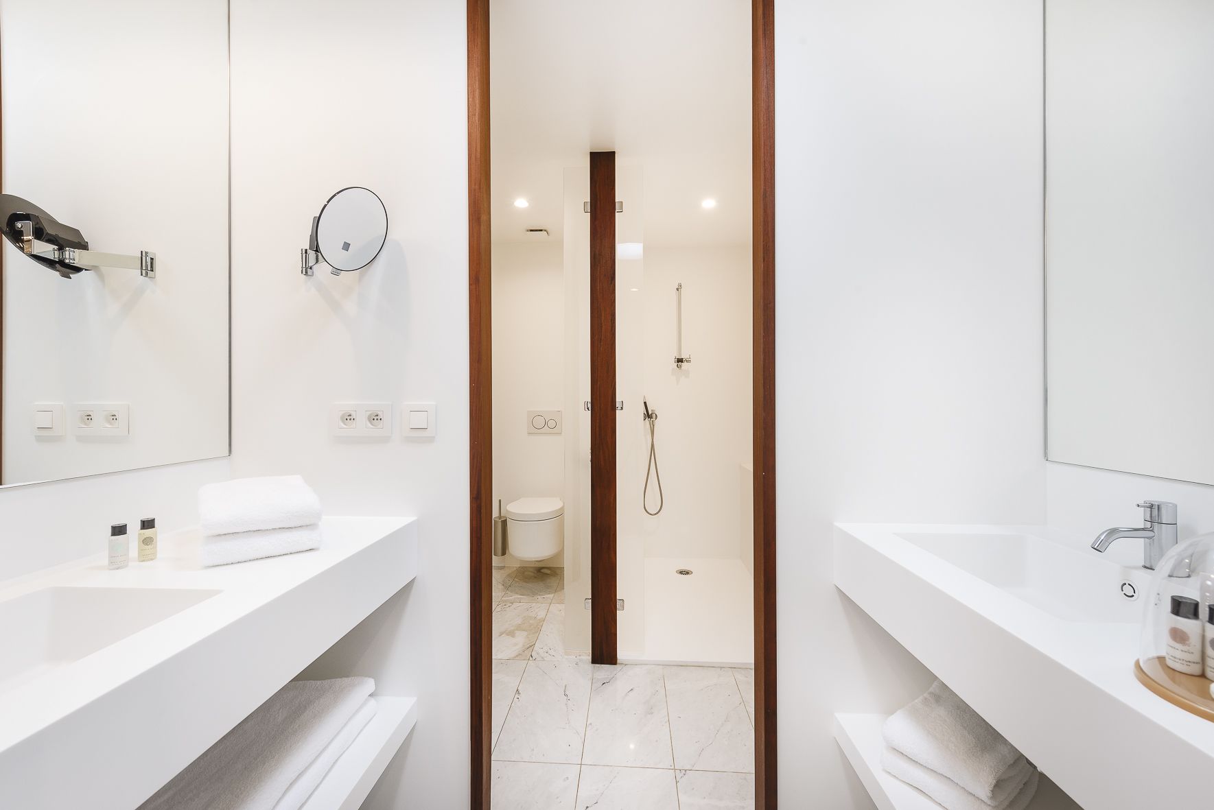 Un baño moderno con dos lavamanos, un espejo, ducha y retrete.
