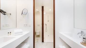 Un baño moderno con dos lavamanos, un espejo, ducha y retrete.