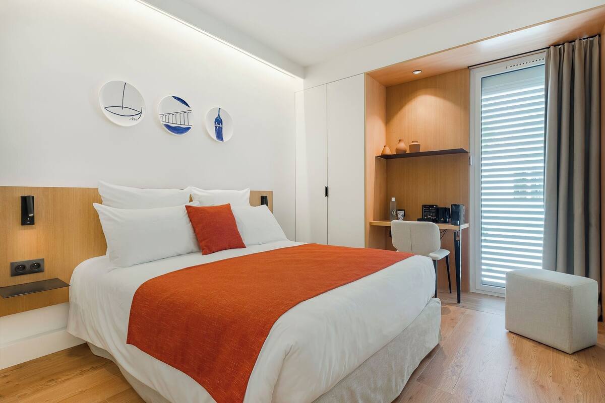 A modern hotel room with a large bed, a desk, and a chair.