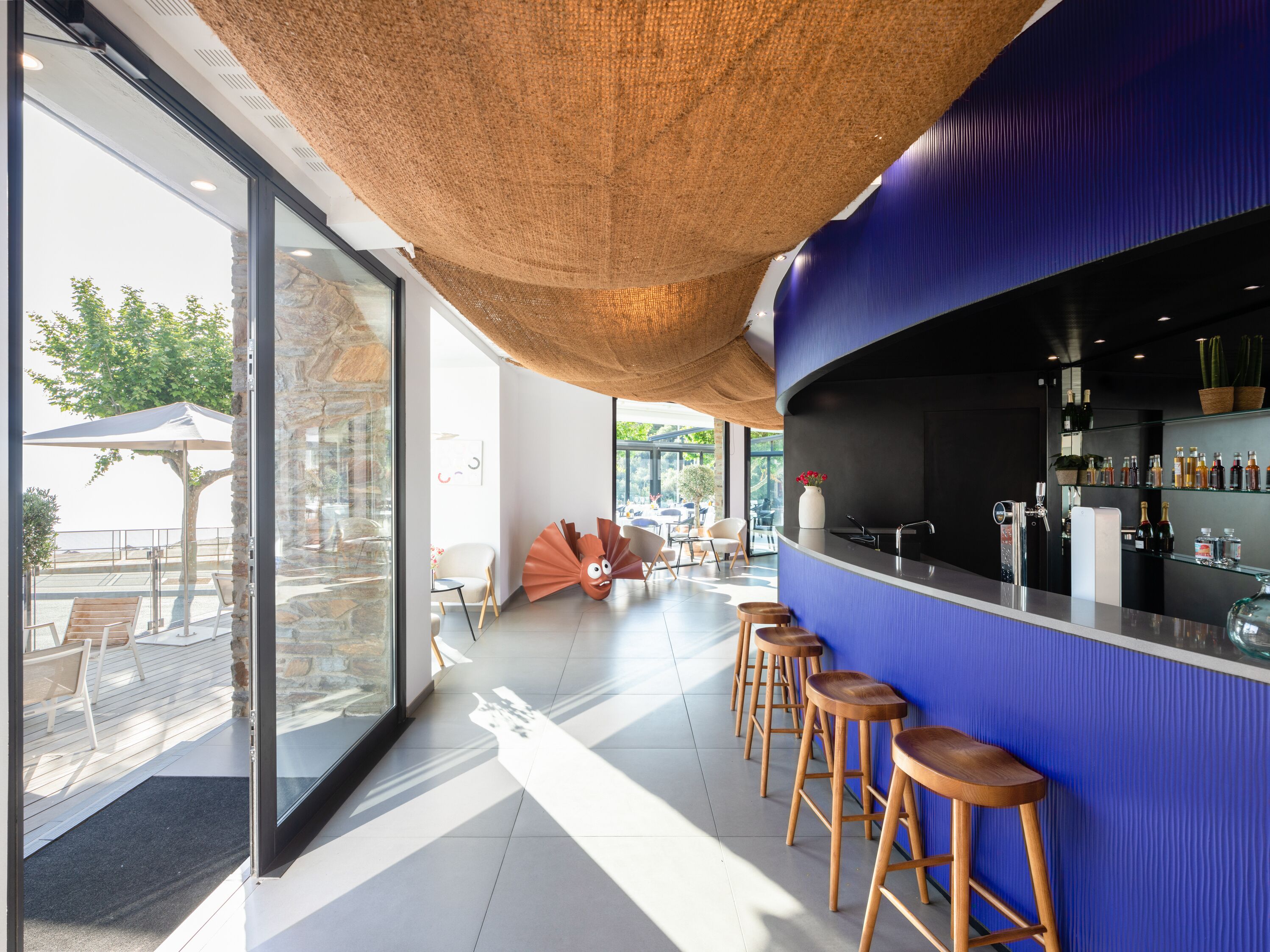 Un área de bar moderna con una pared azul de acento, una pared de piedra y un paraguas grande.