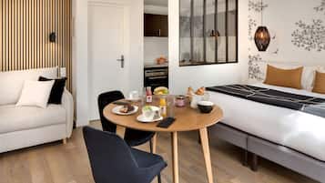 Une chambre moderne comprenant un lit, une table à manger avec des aliments pour le petit-déjeuner, un canapé et un coin cuisine.