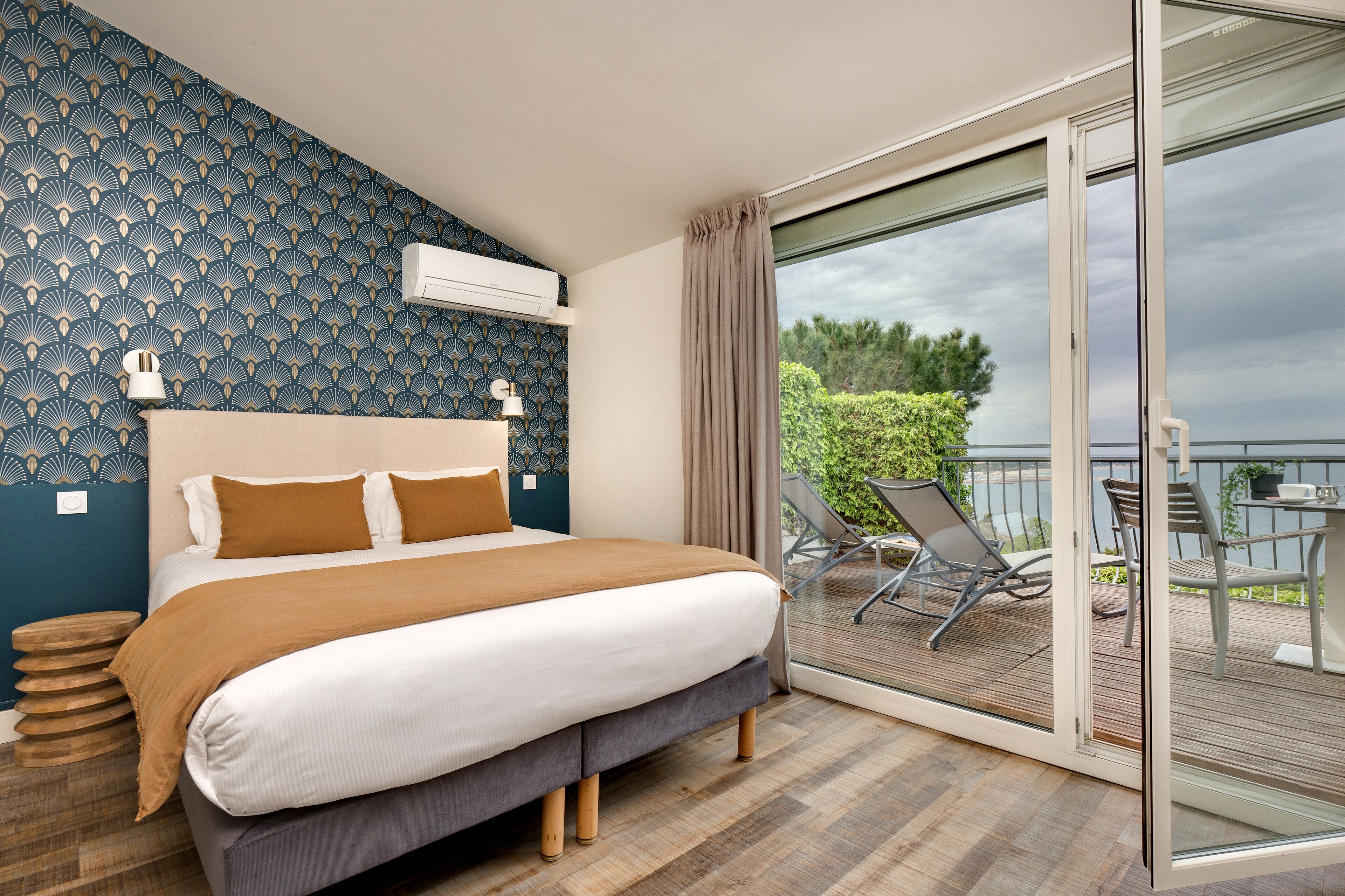 A bedroom with a bed, a window, and a balcony with chairs.