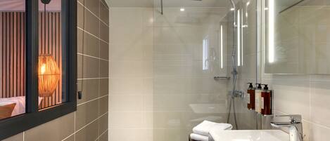 A modern bathroom with a glass-enclosed shower, a white sink, and a large mirror.