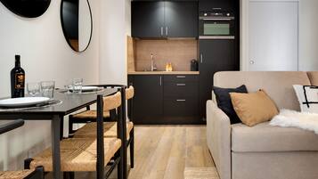 A compact living space with a dining area, kitchenette, and a sofa with cushions.