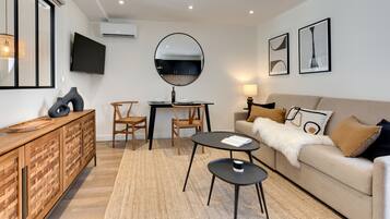 Una sala de estar moderna con un sofá, dos sillones, una mesa de centro, un televisor y una mesa de comedor.