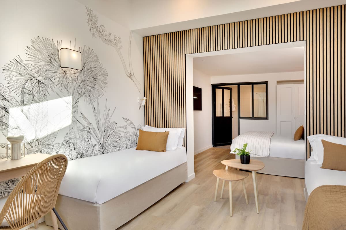 A modern hotel room with two beds, a desk, and a chair.