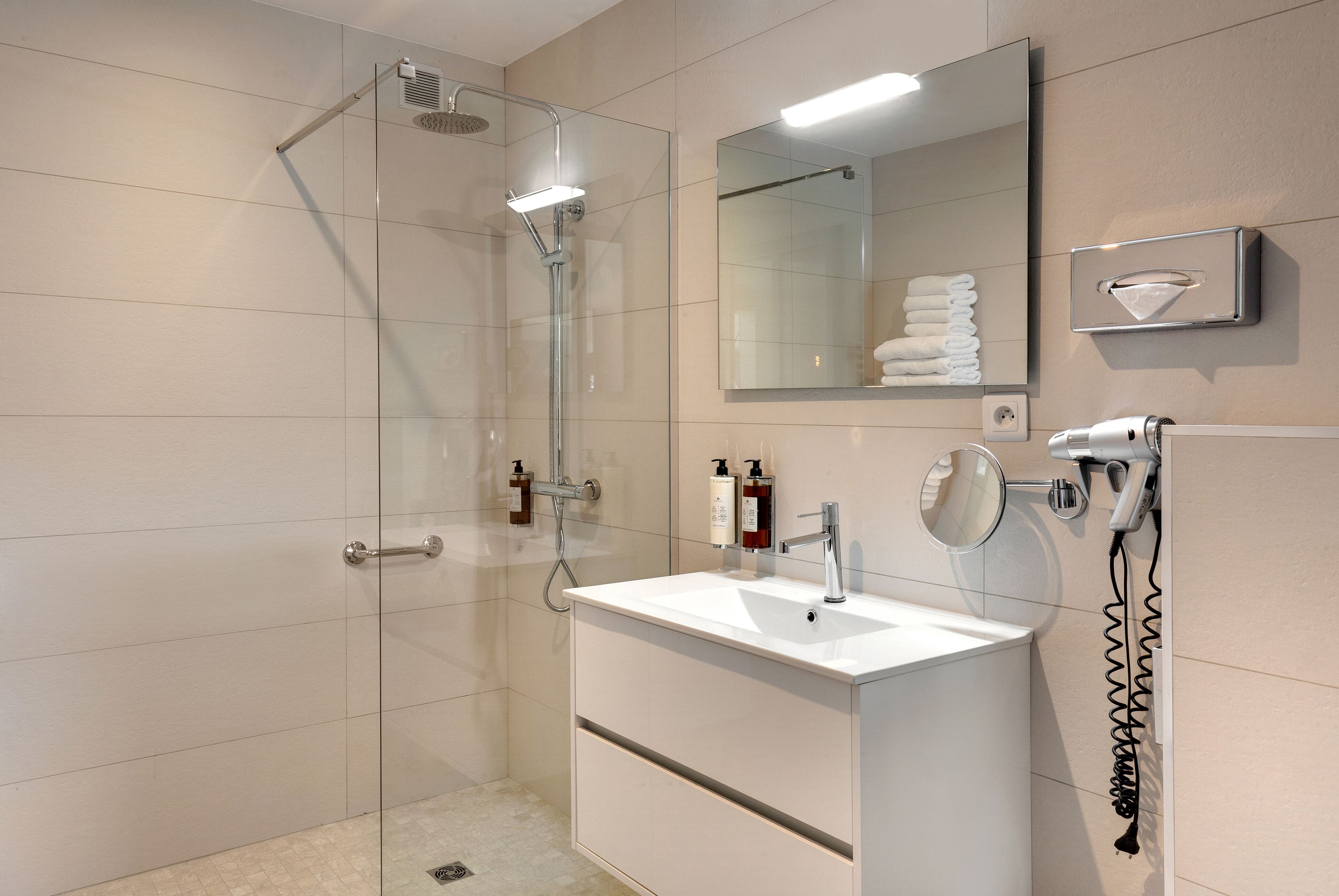 A modern bathroom with a glass-enclosed shower, a white sink, and a mirror above it.