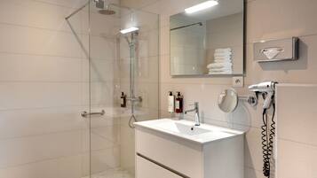 A modern bathroom with a glass-enclosed shower, a white sink, and a mirror above it.