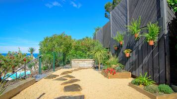 A garden with a gravel path, potted plants, and a wooden bench.