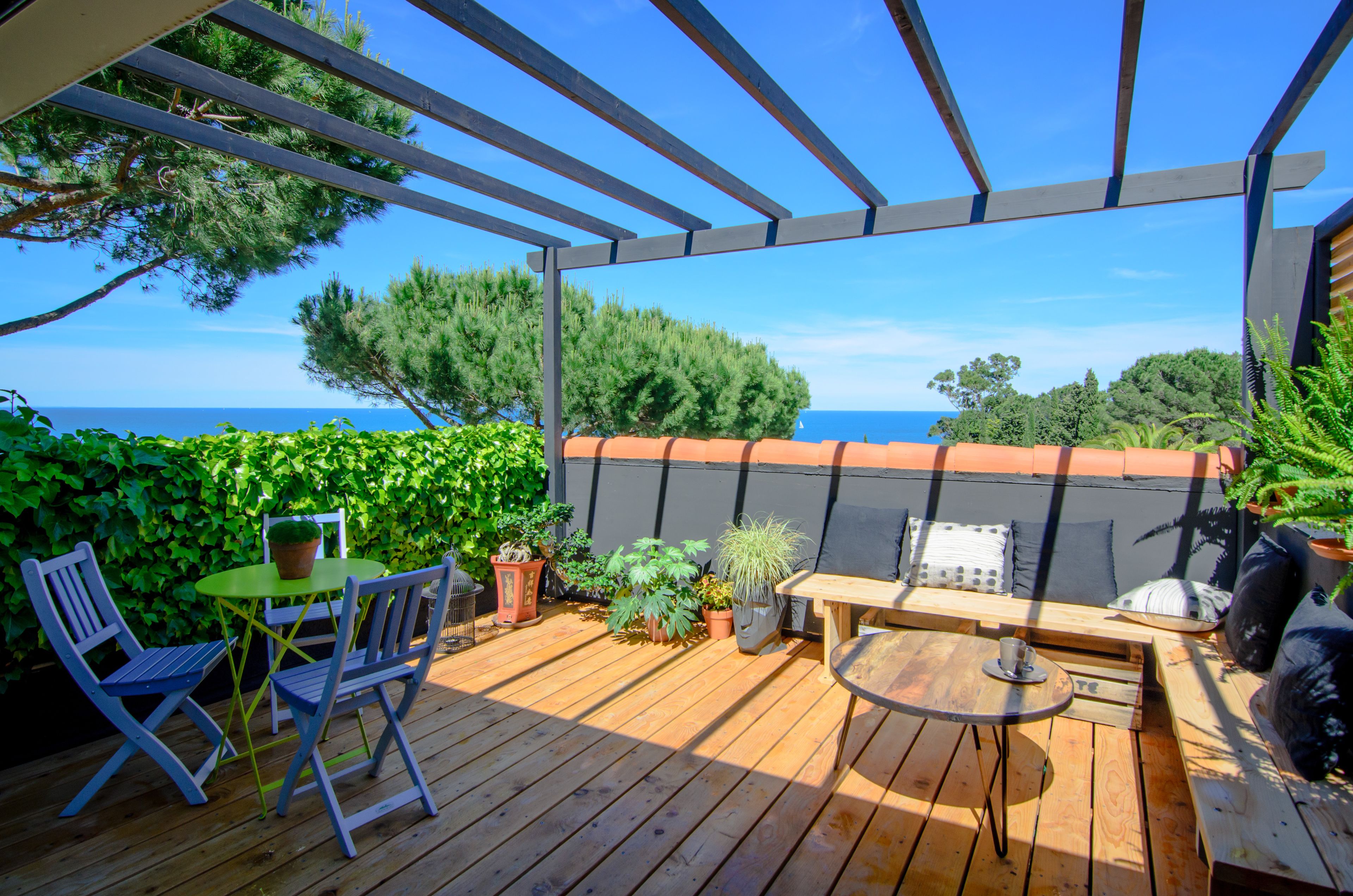 Une terrasse en bois agrémentée d’une pergola, de meubles d’extérieur et de plantes en pot.
