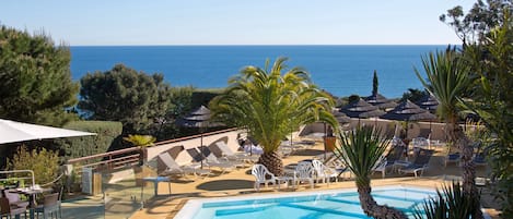 Una piscina al aire libre, sombrillas, tumbonas