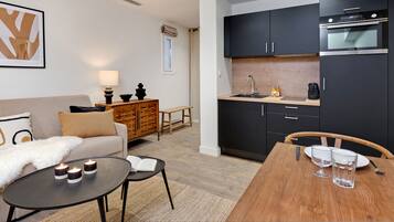 Una sala de estar moderna con un sofá, una mesa de centro con velas y un comedor con una mesa de madera y sillas.