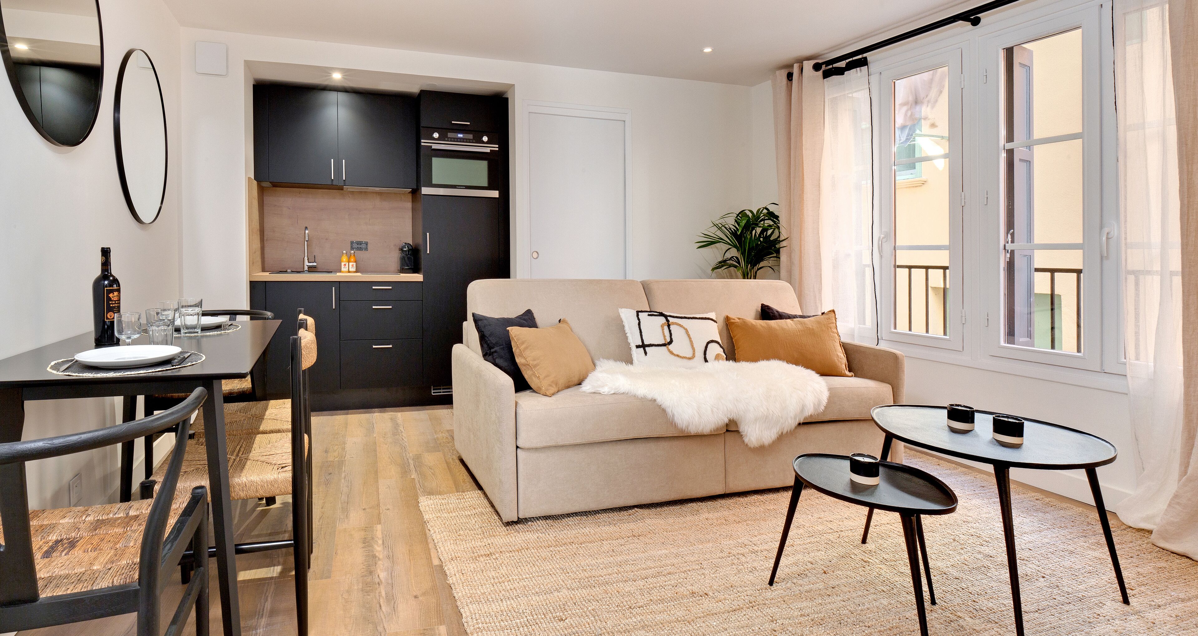 Ein modernes Wohnzimmer mit einer Couch, zwei Beistelltischen und einem Essbereich mit Stühlen und einem Tisch.