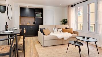 Ein modernes Wohnzimmer mit einer Couch, zwei Beistelltischen und einem Essbereich mit Stühlen und einem Tisch.