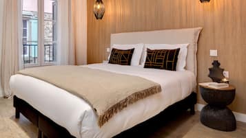 A hotel room with a large bed, a bedside table with a lamp, and a view of the outside balcony.
