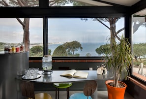 Una mesa con vista al mar, una planta en maceta y un libro.