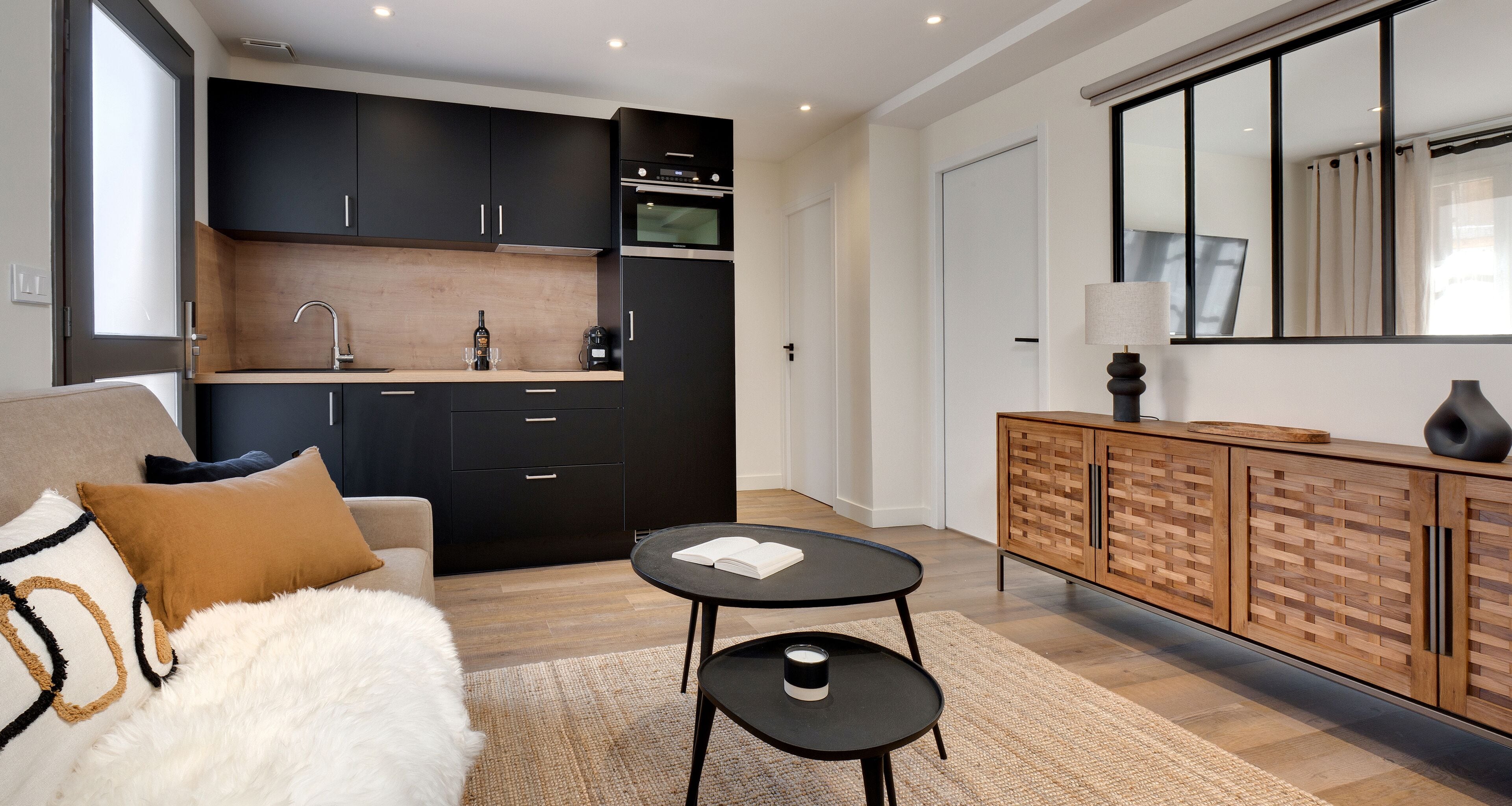Une cuisine moderne avec des meubles de couleur sombre, un plan de travail en bois et un four encastré.