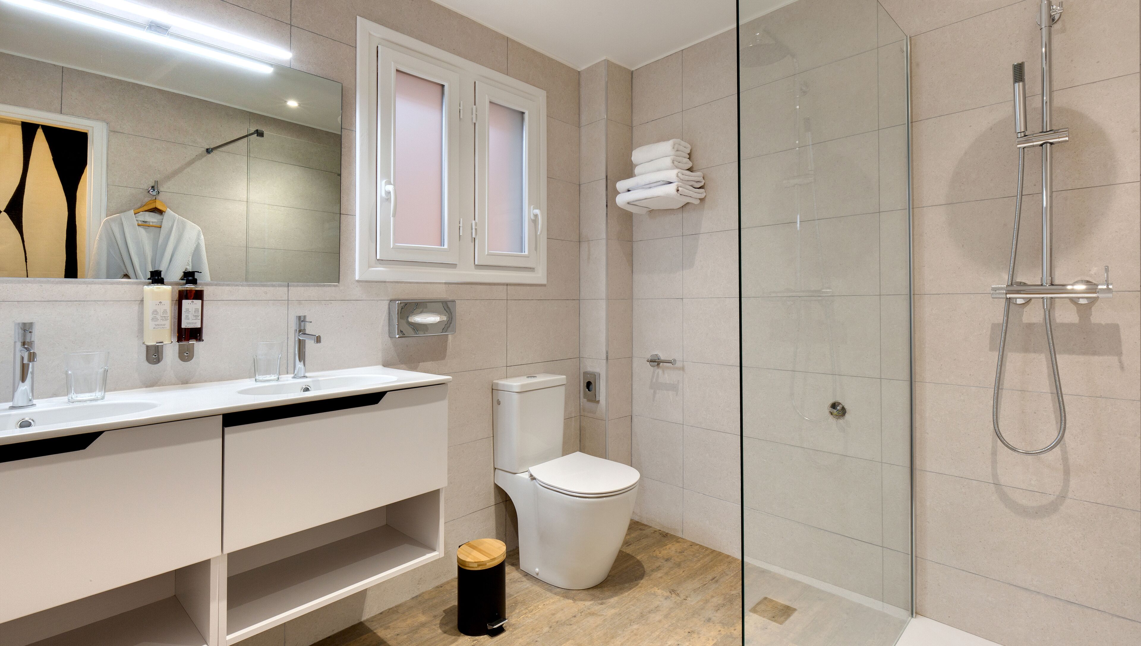 A modern bathroom with a glass-enclosed shower, a white sink with a mirror, and a toilet.